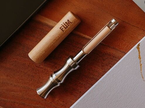 FÜM Prominent opened on a wooden table, with a flavor core in the mouthpiece cradle and the maple barrel beside it